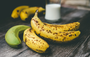 Ripe bananas on a wooden table with milk