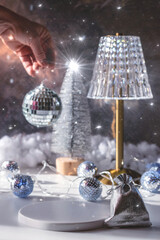 Christmas or New Year background. Lamp on the table and Christmas tree. Disco ball in hand.