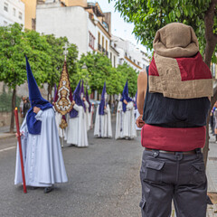 Obraz premium Costalero with his back turned with the procession parade out of focus during Holy Week in Cordoba, Spain
