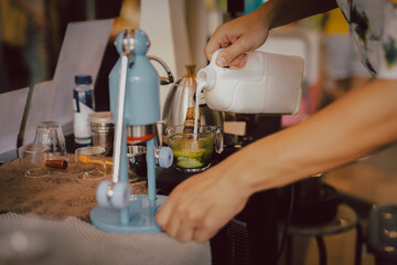 Obraz na płótnie Canvas Barista preparing matcha latte with hand pouring milk in cafe.