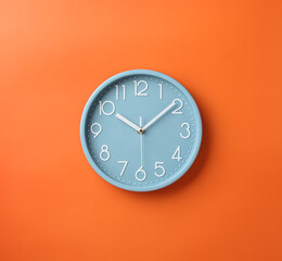 wall clock on orange paper background with copy space