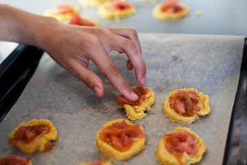 girl puts apple jam on shortbread cookies with her hands
