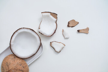 Fresh coconut and white ceramic plate on minimalist background. Scenes for advertising products with natural origins. View from above, flat lay.