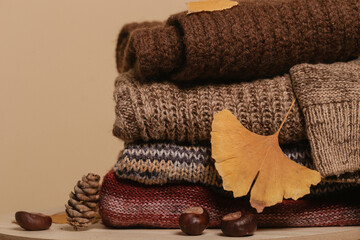 Pile of knitted wool sweaters with autumn dry leaves. Winter autumn cozy season concept.	