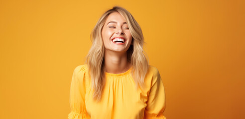 a blonde woman in a yellow dress on an apricot background laughs and rejoices - obrazy, fototapety, plakaty