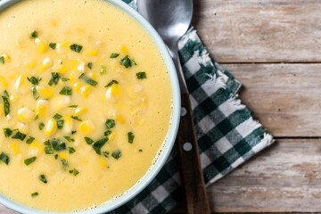 Corn soup in green bowl on wooden table. Top view. Copy space