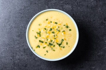 Corn soup in green bowl on black background. Top view