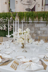 Wedding in palace style.White wedding table with luxurious setting, bouquet of roses on terrace.