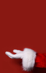 Santa Claus hand presenting your text, product, advertisement on a red background.Mockup. Copy space.