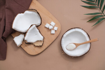 Fresh coconuts are displayed on wooden cutting boards, purple cloth towels and other props on a pastel purple background. Mockup for product advertising with fresh coconut as an ingredient.