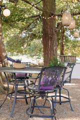 Great place to relax in nature.Wrought-iron black table and chairs on gravel area with tall trees .