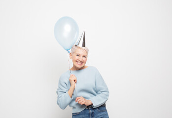 Naklejka premium Portrait of elderly lady holding blue balloon having fun