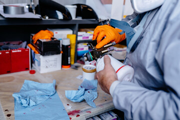 Close up of male hands pour the paint into the spray gun at car service center auto repair body paint workshop.