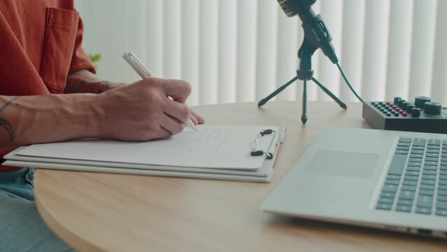 Medium shot of pensive editor writing notes on wireless laptop while preparing for interview with famous person in studio
