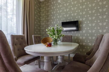 The interior of a modern light dining room with a long oval table surrounded by seats