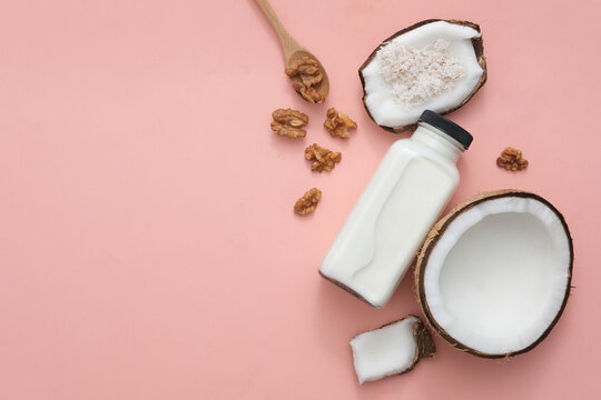 A bottle of nut milk, walnuts and fresh coconut are placed on the right side of the frame, with space on the left for inserting product images or text designs. Nut milk is very good for health.