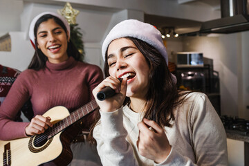 Latin friends singing in karaoke party celebrating christmas at home in Mexico Latin America