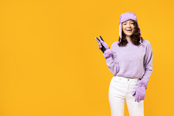 A woman in a warm ski suit on a yellow background.