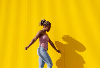 young beautiful woman with a long braids posing on a yellow background
