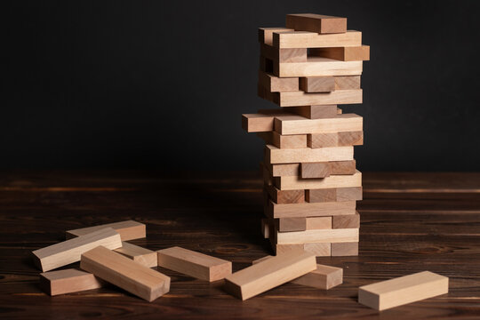 Jenga tower made of wooden blocks on wooden background, space for text