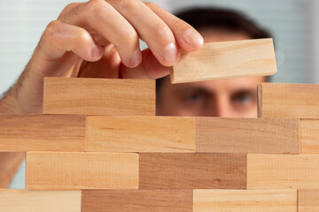 Man holding blocks wood game jenga Build wall. close up