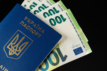 ukrainian passport and 100 euro banknotes on black background