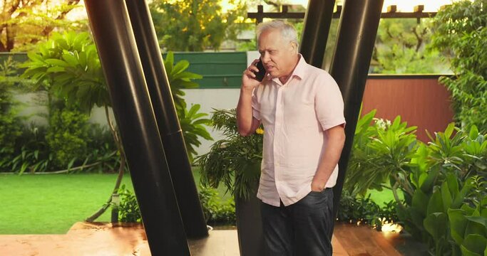 Indian Asian Hindu old elder upset sad angry boss man male client walking house home park talk speak on call mobile phone alone middle aged older tensed stress grandpa using device share bad news