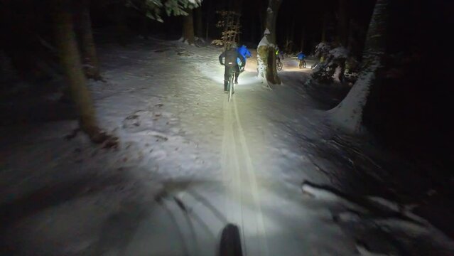 downhill ride on a slippery mtb path in the forest on the night of winter with fresh snow 