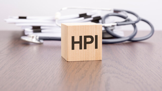 text HPI is written on wooden cube near a stethoscope on a dark background