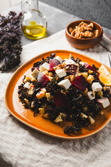 Salad of kale, roasted beets, walnuts and feta cheese on the table vertical photo