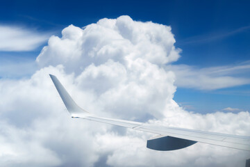 Fototapeta na wymiar beautiful blue sky with soft clouds and plane wing as abstract background, bird's-eye view from an airplane window, travel concept