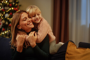 Daughter hugging her mother on the sofa