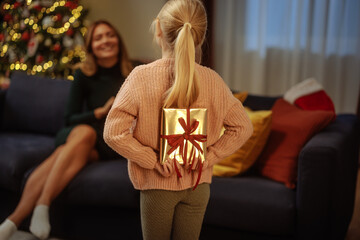 Daughter approaching mother with a present - obrazy, fototapety, plakaty