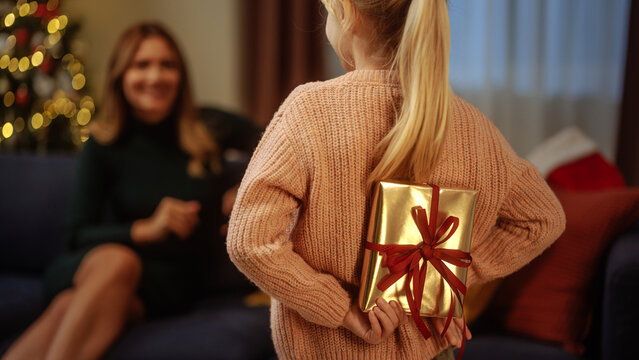 Little girl holding a gift to surprise her mother