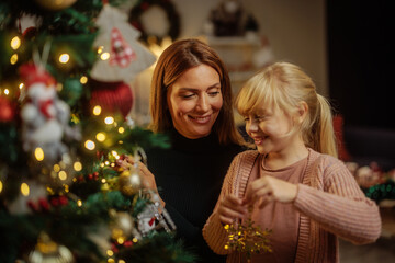 Happy mother and daughter decorating a Christmas tree