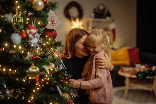 Mother and her happy daughter decorating a Christmas tree