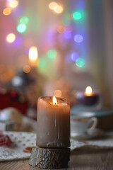Various colorful Christmas decorations, soft blanket, cup of tea, sweet snacks and lit candles on the table. Cozy Christmas atmosphere at home. Selective focus.