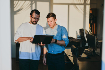 Portrait of two professional male programmers working on computer in diverse offices. Modern IT...