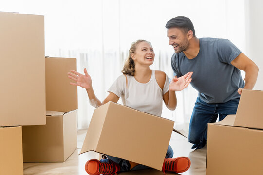 a happy family. a cheerful guy and a girl are sorting out boxes in a new house, a cheerful couple is joking and laughing
