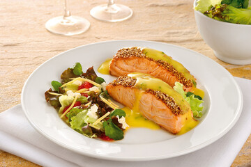 mesa com prato com salmão com crosta de gergelim e calda de laranja acompanhado de salada de mix de folhas