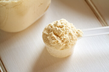 Vanilla flavored whey protein powder in a plastic measuring cup