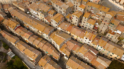 Aerial view of the sloping roofs of the houses in the historic center of Bracciano, in the metropolitan city of Rome, Italy. The orange color of traditional roofs predominates.