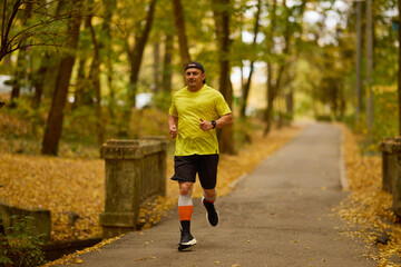 Portrait of a middle-aged man running in the park on an autumn day.