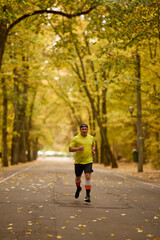 Obraz premium Portrait of a middle-aged man running in the park on an autumn day.