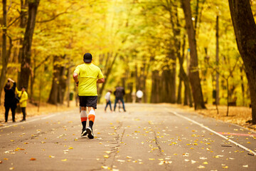 Fototapeta premium Portrait of a middle-aged man running in the park on an autumn day.
