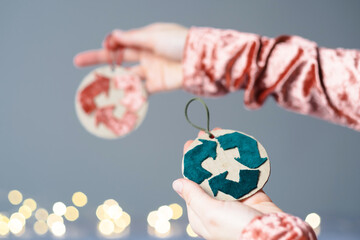 Creative symbol of clothing recycling. A woman holding a eco Christmas tree decoration on the background lights. Ecological and sustainable fashion.