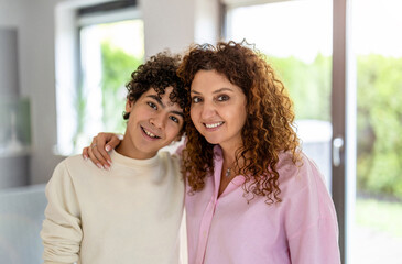 Portrait of smiling mother and son standing in living room at home
