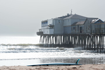 Surfboard laying on the beach near historic Old Orchard Pier at Old Orchard Beach in York County,...