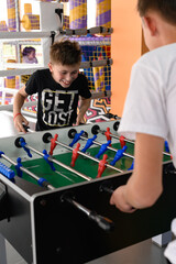 Two boys are playing table football in the playroom