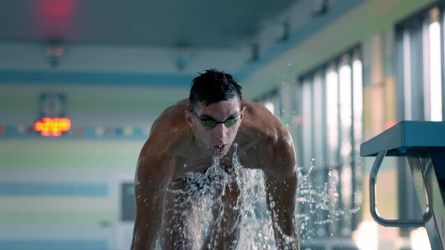 Handsome man with goggles jumps out of pool at training